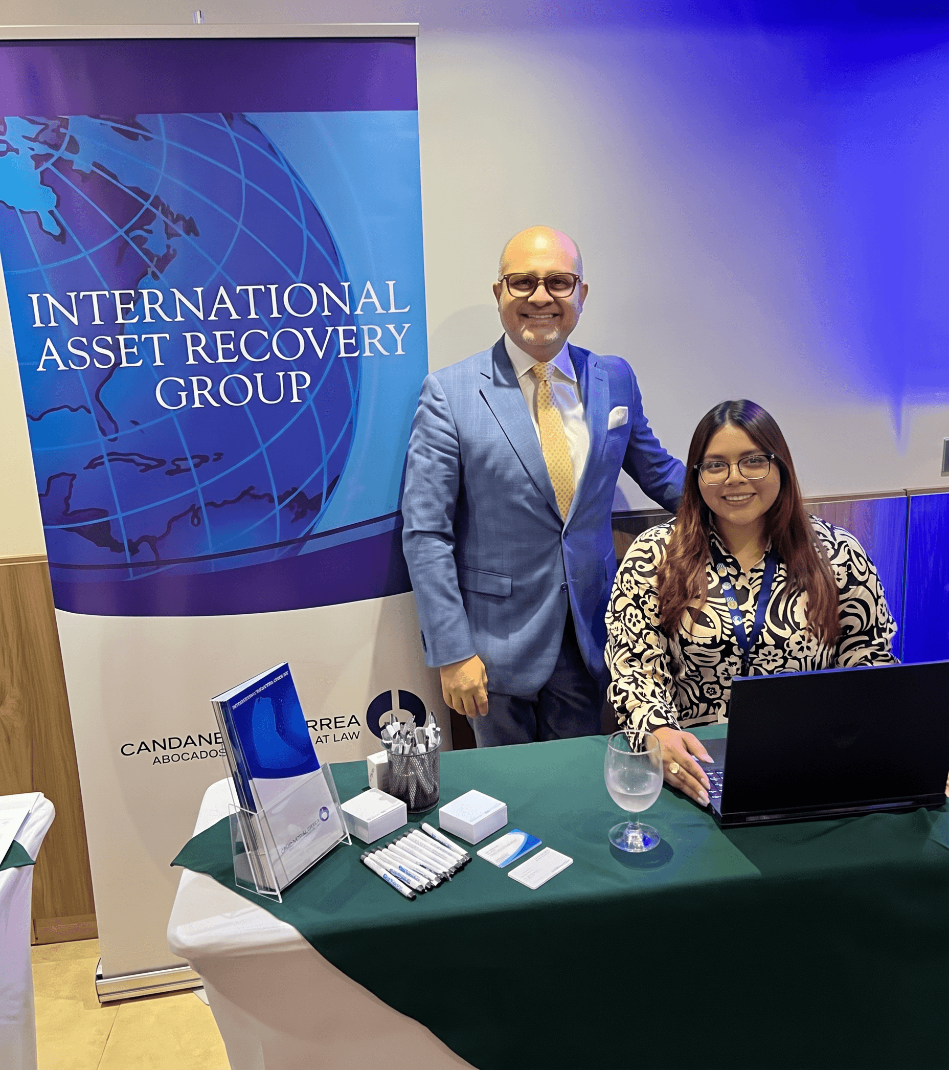Smiling man and woman at a promotional table for the International Asset Recovery Group.